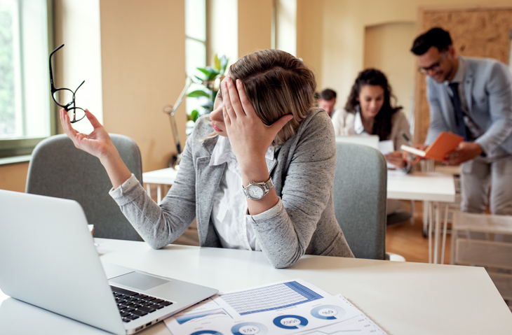 Portrait of young businesswoman working on a laptop at the office. Poor sales from company being felt as stressed employee looks weary.